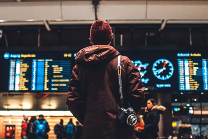 Hombre en el aeropuerto consultando horarios de Salidas (Erik Odiin Unsplash)